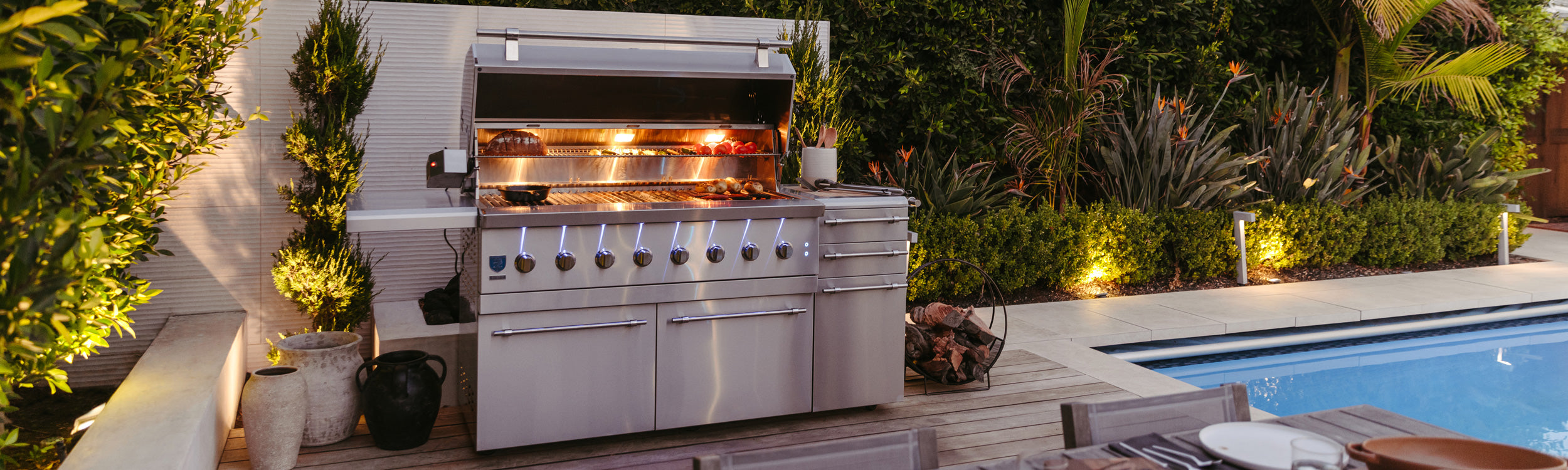 Premium backyard outdoor kitchen with built-in gas grill, charcoal smoker, pizza oven, and side burners.